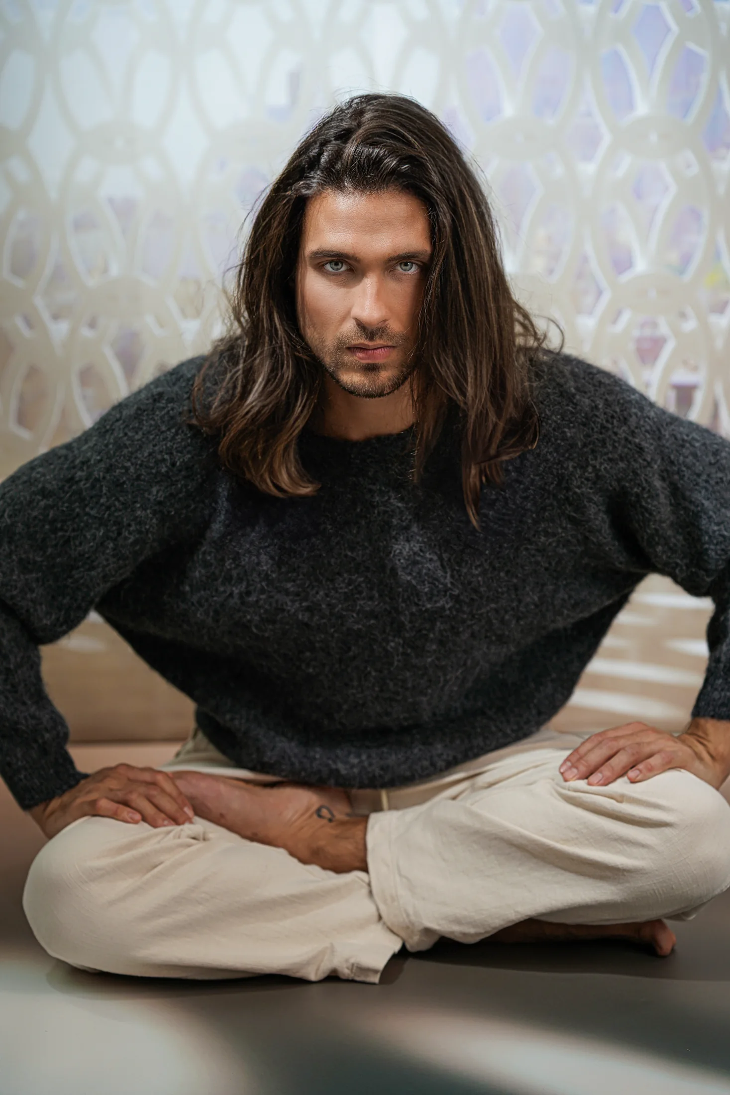 Alexander entspannt sitzend im dunklen Stricklook mit ruhigem, direktem Blick